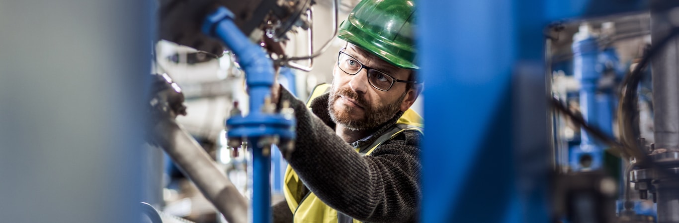 Field engineer inspecting valve actuator on plant piping